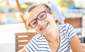 Smiling young girl wearing eyeglasses and dental braces