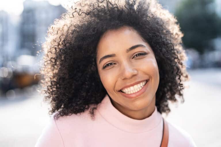 Happy afro american young woman smiling at camera outside - Close up portrait of brazilian female laughing on city street